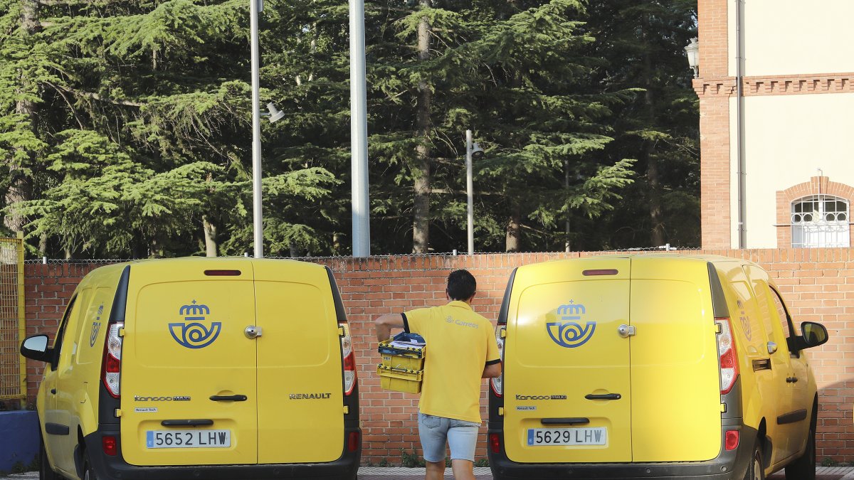 Un repartidor de Correos, en Palencia, se dispone a cargar una caja con cartas en un vehículo