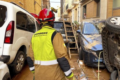 Un bombero ante los coches arrastrados y amontonados por la Dana.