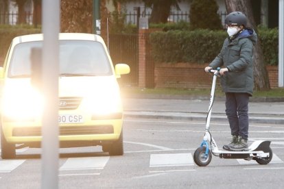 Un joven con un patinete cruza un paso de peatones en una calle de Valladolid. J.M. LOSTAU