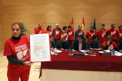 Una de las portavoces de los afectados, Esther Mate, sostiene el documento suscrito por PSOE, Podemos, Izquierda Unida, Ciudadanos y UPL en apoyo de los afectados por la Hepatitis C-Ical