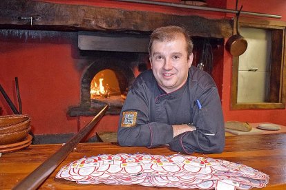 Sergio Blázquez, junto a la boca del horno de asar, con contraetiquetas de lechazo asado.-ARGICOMUNICACIÓN