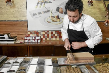 El pastelero Julián Arranz corta una porción de turrón artesano en el mostrador del obrador de Pedrajas de San Esteban.-J.M. LOSTAU