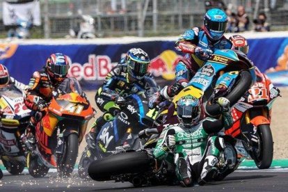 Àlex Márquez (Kalex), a la derecha, con casco azul, salta, vuela, por encima de la moto y el cuerpo del australiano Remy Gardner, sentado ya en la pista tras su caída, en la salida de hoy de Moto2, en Jerez.-ALEJANDRO CERESUELA