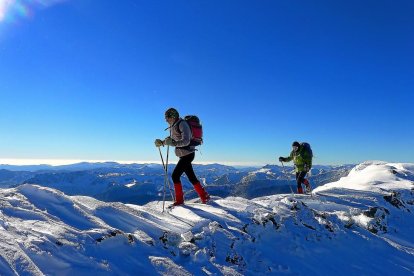 Arriba, dos montañeros progresan por la ancha arista y, a la izquierda, contemplan la vista desde la cumbre de Estorbín de Valverde.-EDUARDO RODRIGO