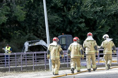 Los bomberos acuden a la zona de la fuga de gas con la pala excavadora al fondo.-J.M. LOSTAU