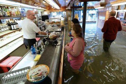 Clientes de un bar, con el agua hasta por encima de las rodillas, este domingo.-AP / ANDREA MEROLA