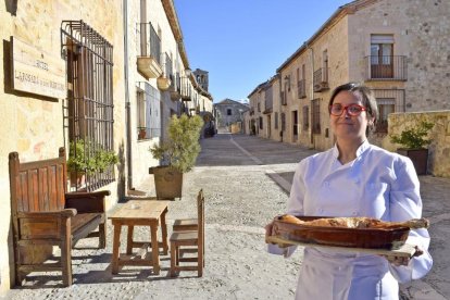 Marta Pascual, con un asado, a la entrada del restaurante, en pleno casco histórico de la villa monumental de Pedraza de la Sierra.-ARGICOMUNICACIÓN