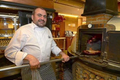 Alberto López  saca un cochinillo del horno de leña del restaurante El Fogón de Salvador.-ÁLVARO MARTÍNEZ