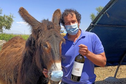 Richard y el burro Sobrenatural, ambos con mascarilla, con una botella de su Menade Verdejo Ecológico.  / ARGICOMUNICACIÓN