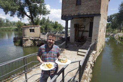 Javier Domínguez posa con dos platos de su cocina, en el exterior de la aceña sobre el río Duero.-J.L.C.