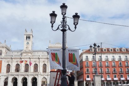 Operarios junto a lonas publicitarias de la semana internacional de cine, Seminci, en la plaza Mayor. / ICAL