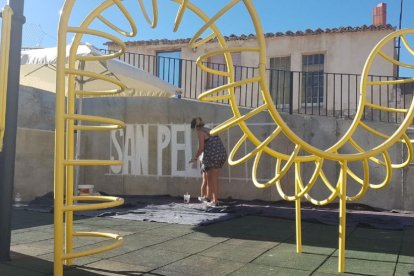 La encargada de coordinar el mural comienza a perfilar el dibujo con el nombre del pueblo.-EL MUNDO