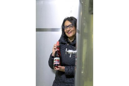 Inés Salas posa con una botella de Piña Picota entre dos depósitos de elaboración.-M.T.