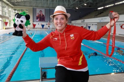 Laura López Valle posa en la piscina de Huerta del Rey -con su foto al fondo- con sus recuerdos de Beijin 2008, la mascota Jingjing y la medalla de plata.-J. M. LOSTAU