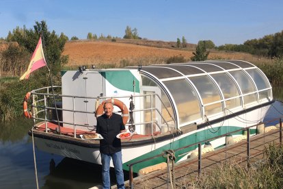 Luis, frente al barco en el Canal de Castilla, con dos de los platos de su comanda.- E.M.