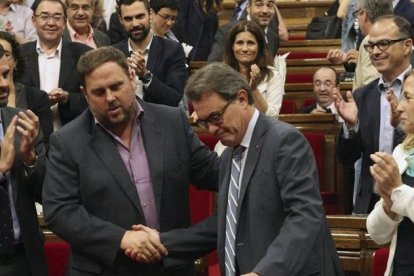 El presidente de la Generalitat, Artur Mas, estrecha la mano del lider de ERC, Oriol Junqueras, ante el aplauso de sus compañeros de partidos, tras la aprobación, hoy en el pleno del Parlamento de Cataluña, de una resolución pactada por los cuatro partido-Foto: EFE / TONI GARRIGA