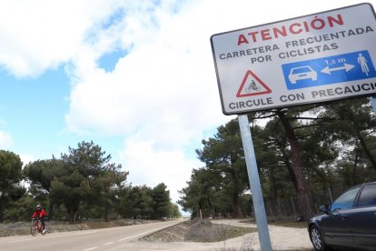 Un ciclista circula por la carretera, donde luce un cartel de precaución.-ICAL