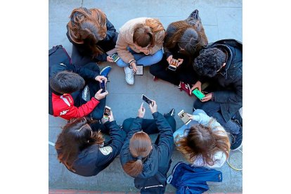 Un grupo de adolescentes interactúan en círculo con sus teléfonos digitales a través de juegos, redes sociales y mensajería. MIGUEL ÁNGEL SANTOS / PHOTOGENIC