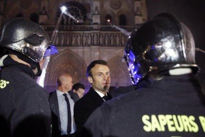 El presidente de Francia  Emmanuel Macron, habla con los bomberos que intentan apagar el incendio en la catedral de Notre Dame, en París, el pasado abril.-YOAN VALAT (EFE)