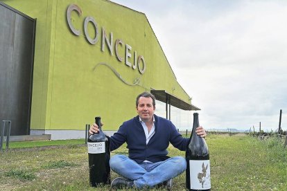 Enrique Concejo posa con dos de sus vinos frente a las instalaciones de su bodega.-