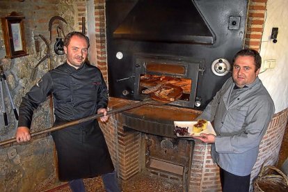 Alfonso y Julio, junto al horno de asar de Los Tarantos y uno de los platos de la bodega-restaurante.-ARGICOMUNICACIÓN