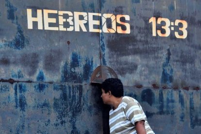 Una mujer observa por una rendija en una puerta del centro penitenciario de Tela, este sábado.-EFE / JOSÉ VALLE