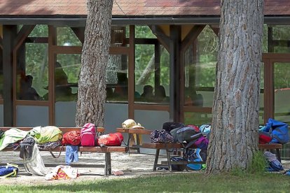 Niños y monitores del campamento en un pabellón, ayer en el área de ocio de Hornillos de Eresma. En el exterior, mochilas y sacos de dormir.-NURIA MONGIL