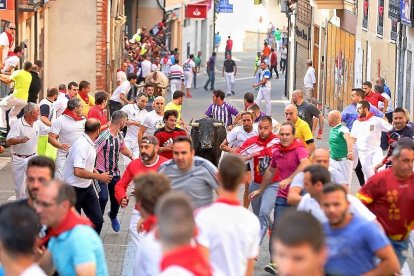 Un grupo de participantes en el encierro durante el recorrido urbano rodean a uno de los toros.-ICAL