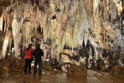 Dos visitantes contemplan la majestuosidad de las estalactitas y estalagmitas en una de las siete salas visitables que conforman el recorrido de las Cuevas de Valporquero.-ANXO RIAL