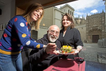 Manuel Sierra sentado entre Natalia Burguillo (i) y Sara Grande (d) se dispone a probar una ensalada con San Gregorio como telón de fondo.-M. A. SANTOS