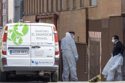 Dos trabajadores de una funeraria se equipan a las puertas del Hospital Clínico. MIGUEL ÁNGEL SANTOS (PHOTOGENIC)