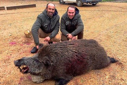 Los dos perreros, junto al jabalí que fue abatido.-LEONARDO DE LA FUENTE