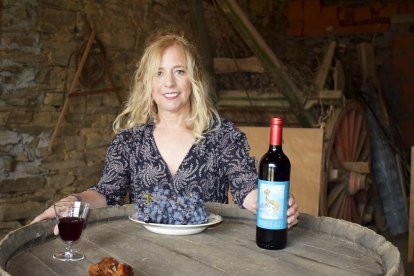 Teodora López en el interior de la bodega familiar con un racimo de uvas de tinta mencía y el primer vino que se embotella en su pueblo.-E. M.