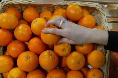 Una persona coge una naranja en un supermercado.-DANNY CAMINAL (ARCHIVO)