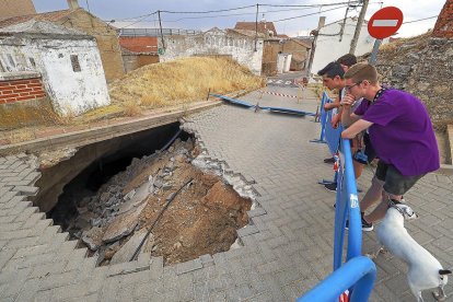 Tres vecinos observan el socavón provocado por el hundimiento de una de las bodegas del casco urbano, ayer en Cabezón.-MIGUEL ÁNGEL SANTOS