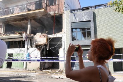 Una mujer fotografía el edificio siniestrado.- J. M. LOSTAU