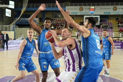 Devin Schmidt penetra entre dos jugadores del Melilla en el último partido del UEMC Real Valladolid saldado con derrota. / J. M. LOSTAU