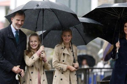 El rey Felipe VI, la princesa Leonor, la infanta Sofía y la reina Letizia, bajo la lluvia, en su visita a Asiegu (Asturias).-EFE/ L. CEREIJIDO