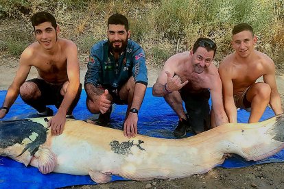 A la izquierda, Enrique Sanz posando con el siluro junto a su hermano y compañeros