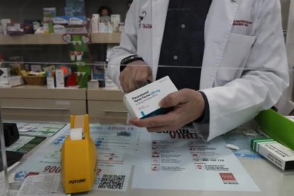 Un farmacéutico con una caja de paracetamol en su farmacia