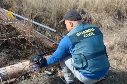 Un agente de la Guardia Civil inspecciona el cableado dañado tras el robo.