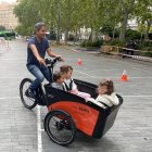 Una persona utiliza una bici adaptada en la que lleva a dos niños.