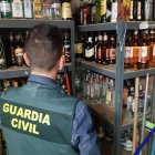 Un agente de la Guardia Civil frente a varias botellas de alcohol
