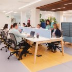 Varias personas alrededor de una mesa con sus portátiles.