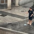 Los dos jóvenes tratando de achicar el agua de la granizada en Valladolid con fregonas y escobas