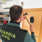 Un agente de la Guardia Civil sujeta el hacha intervenida al investigado.
