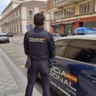 Agente del Cuerpo Nacional de Policía de Valladolid junto a un coche patruila.