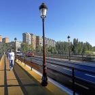 Un peatón camina por una de las aceras del puente Mayor tras cambiar el cemento por caucho.-J.M. LOSTAU