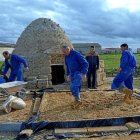 Varias personas se afanan en la restauración de una bóveda de barro en un tradicional chozo de era.-E. M.