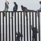 Miembros de la caravana de migrantes que cruzó México a pie hasta la frontera con Estados Unidos trepan el muro fronterizo que separa ambos países el pasado 29 de abril del 2018.-SANDY HUFFAKER (AFP)